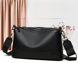 Detalle del bolso bandolera de cuero negro con tres compartimentos con cremallera