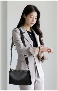 Detailed view of a black genuine cowhide leather crossbody bag on an Asian model