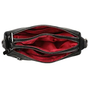 Interior view of black genuine leather crossbody bag with multiple compartments and red lining
