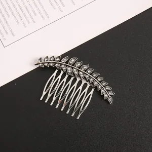 Close-up detail of a silver leaf-shaped hair comb with clear crystal inlays