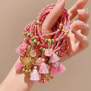 Macro view of pink braided DIY jewelry cords with cute cartoon charms and tassels
