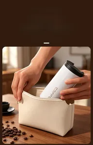 Macro view of a portable white coffee thermos being placed into a stylish cream bag.