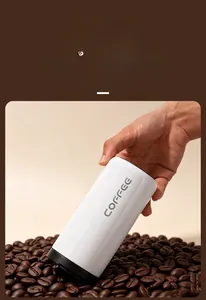 Hand holding a sleek white insulated coffee tumbler over premium roasted coffee beans