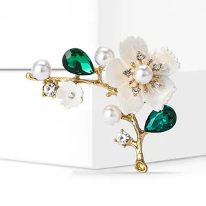 Detailed macro shot of white cherry blossom brooch with green crystals and pearls