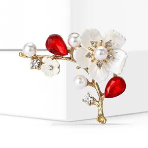 Detailed macro view of an elegant cherry blossom brooch with red crystals and pearls