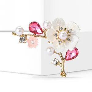 Detail shot of cherry blossom brooch with pink crystals and pearls on gold branch
