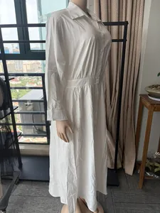 Vue de côté d'une robe chemise blanche à manches longues avec taille cintrée sur mannequin.