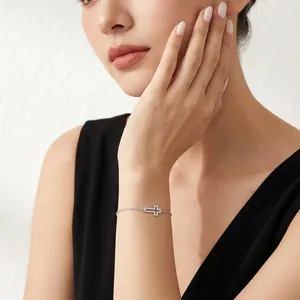 Bracelet croix élégant en argent 925 avec pierres moissanite porté par une femme