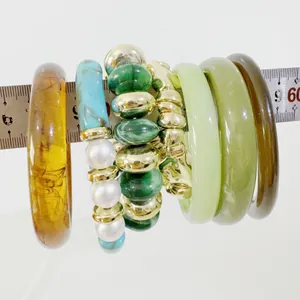 Detailed view of green marbled resin bangles and beaded bracelets on a scale ruler