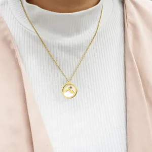 Close-up of golden stainless steel mustard seed mountain necklace worn on a white turtleneck