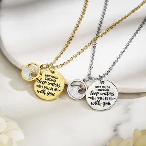 Macro view of stainless steel inspirational necklaces with engraved quote and shell inlay detail.