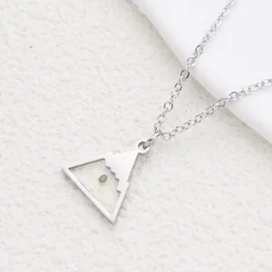 Close-up of stainless steel necklace featuring a mountain pendant with mustard seed
