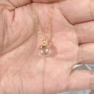 Detailed view of gold mustard seed necklace pendant in clear glass ball