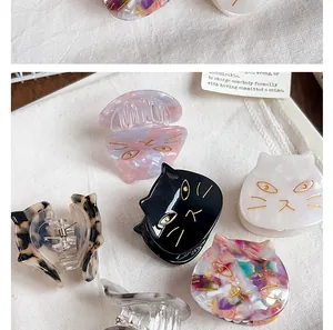 Detailed macro view of colorful cat-shaped acetate hair claw clips on white linen background