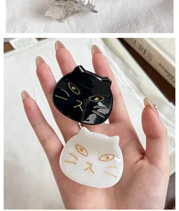 Detailed view of cute black and white cat-shaped acetate hair clips held in a hand