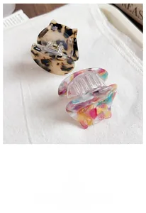 Detailed view of cute cat-shaped acetate hair claw clips in tortoiseshell and floral.