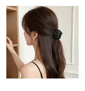 Detailed side view of a cute black cat acetate hair claw clip worn on a ponytail hair style