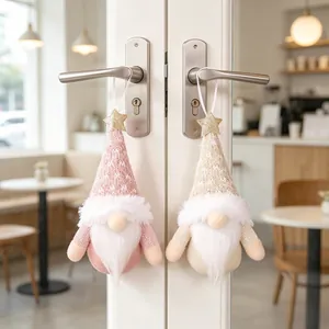 Detailed shot of pink and beige Christmas gnome ornaments hanging on silver door handles.