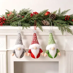 Set of three Christmas fabric forest gnome ornaments hanging on a festive mantel