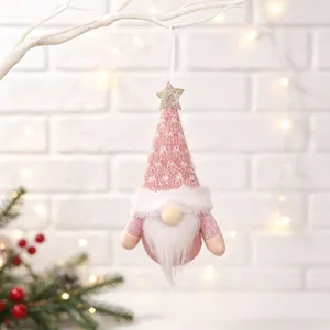 Detail shot of a pink knitted Christmas gnome plush ornament hanging on a white branch
