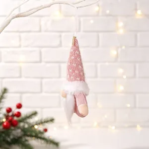 Detail of a pink knitted Christmas gnome hanging ornament with warm bokeh lights