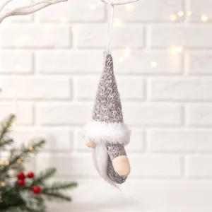 Detail of a grey and white knitted Christmas gnome plush ornament hanging on a branch