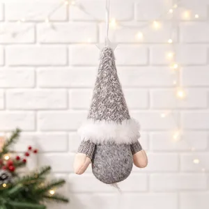 Close-up of a grey plush Christmas gnome hanging ornament against a warm festive backdrop