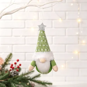 Close-up of green Christmas gnome hanging ornament with silver star on white branch