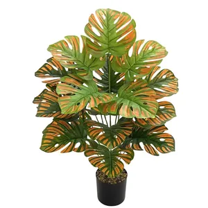 Lifelike artificial Monstera plant with orange and green variegated leaves in a black pot