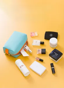 Vue détaillée du sac à cosmétiques en PU cyan entouré de divers produits de luxe