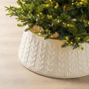 Detail view of elegant cream cable knit Christmas tree collar on a light wooden floor