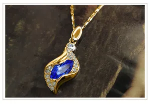 Detailed macro view of gold pendant necklace with marquise blue stone and tiny diamonds