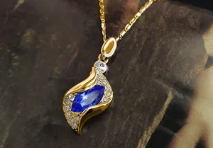 Vue détaillée du collier doré avec pierre marquise bleue et petits diamants brillants