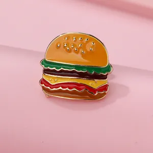 Detailed view of creative burger enamel pin with vibrant layered colors and gold metal edges