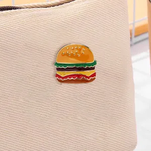 Close-up of burger enamel pin with vibrant colors on beige canvas bag background
