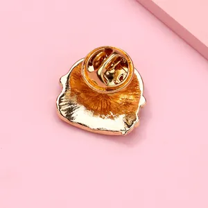 Close-up of golden metal brooch back with secure butterfly clutch on pink surface