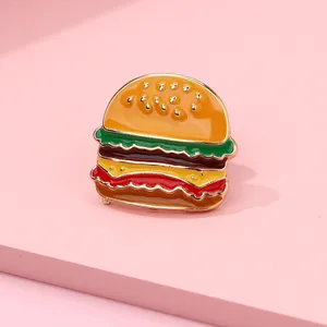 Detail of creative burger enamel pin with vibrant colors and golden metal edges