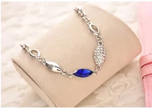 Detailed view of silver-tone bracelet with dark blue marquise crystal on a velvet cushion