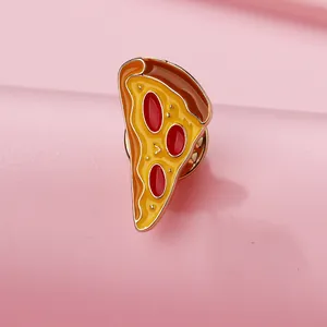 Detailed close-up of a pizza enamel pin with gold plating on a pink background
