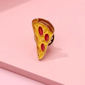 Macro shot of creative pizza enamel pin on a pink geometric background with golden plating