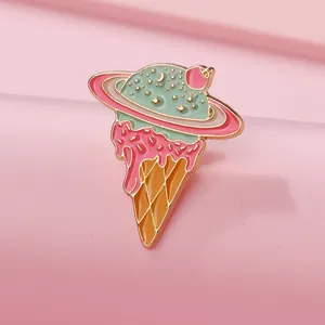 Macro shot of mint ice cream planet enamel pin with golden metal details on pink stairs
