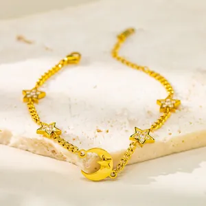 Macro shot of gold star and crescent moon pendants with pavé zircons on a steel chain