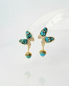 Detailed view of turquoise butterfly earrings with zircon accents and gold hardware