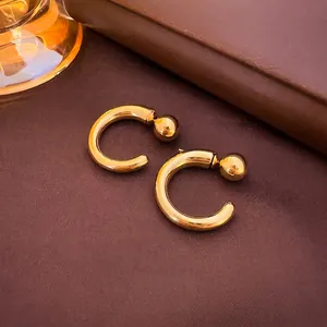 Detailed close-up of golden C-shaped geometric stud earrings on a dark leather texture