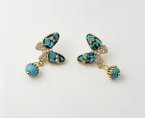 Detail of butterfly turquoise earrings with gold base, pearls and small zircon crystals