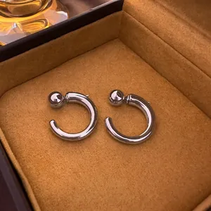 Minimalist silver geometric C-shaped stud earrings displayed on orange velvet background