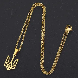 Detail of gold stainless steel necklace with Ukraine Tryzub pendant on black surface