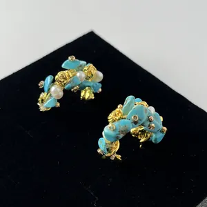 Detailed view of vintage C-shape gold earrings with blue turquoise and white pearls