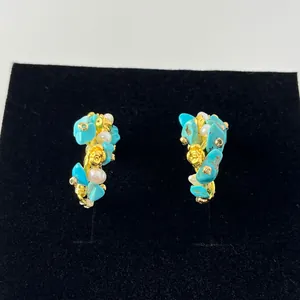 Detail view of turquoise and pearl cluster earrings with gold rose on black velvet