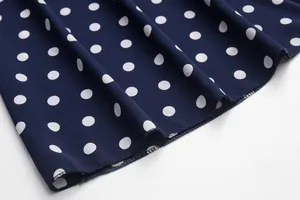 Close-up of navy blue polka dot dress fabric showing quality sewing and texture